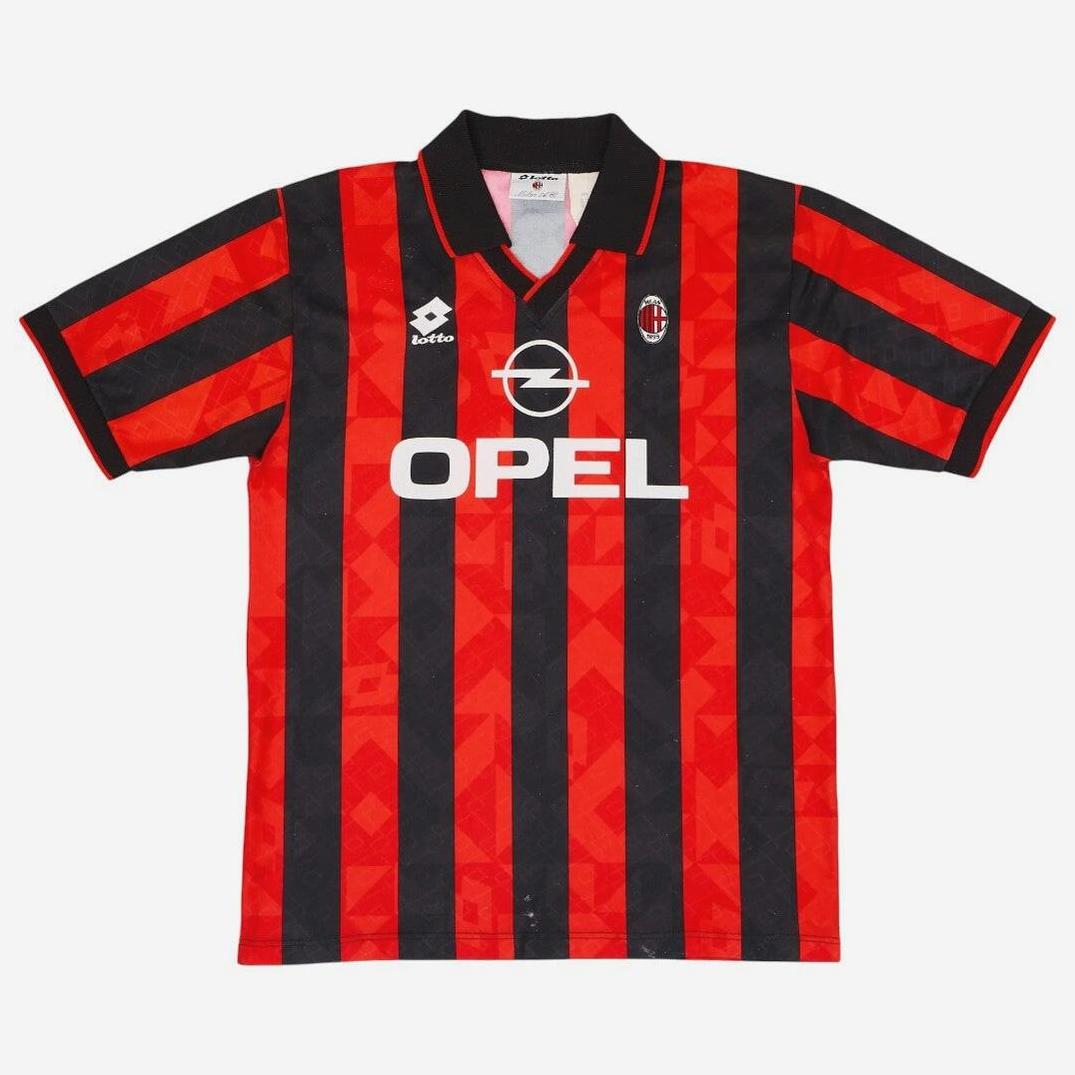 The AC Milan 1995-96 Home Shirt by Retro1999 features red and black stripes, a black collar, Lotto logo, Opel sponsor, club crest on the chest, and subtle geometric patterns for a classic Serie A retro look.