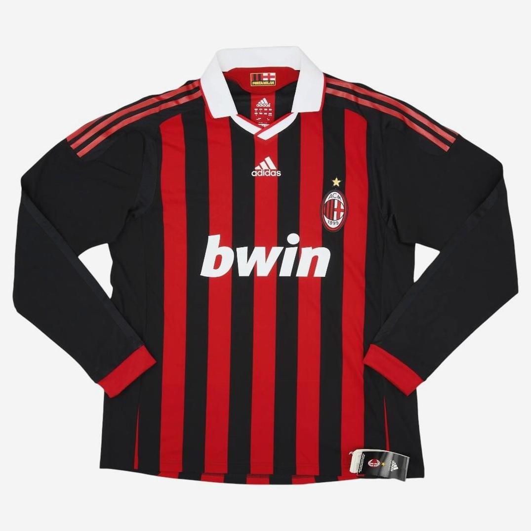 The AC Milan 2009-10 Longsleeve Home Shirt by Retro1999 features classic black and red stripes, a white collar, AC Milan crest, Adidas logo, and bwin sponsor—capturing football heritage in a timeless retro design laid flat on a white background.