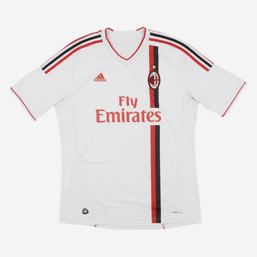 The Retro1999 AC Milan 2011-12 Away Shirt features a white design with red and black accents, the club crest, and sponsor details—an iconic football fashion choice for any fan.