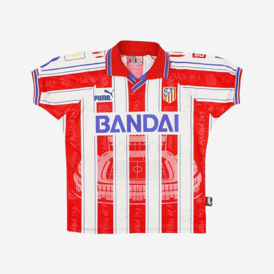 The Atletico Madrid 1996-97 Home Shirt by Retro1999 features iconic red and white stripes, BANDAI sponsor, stadium graphic, blue accents, and club crest—a classic piece from La Liga history.