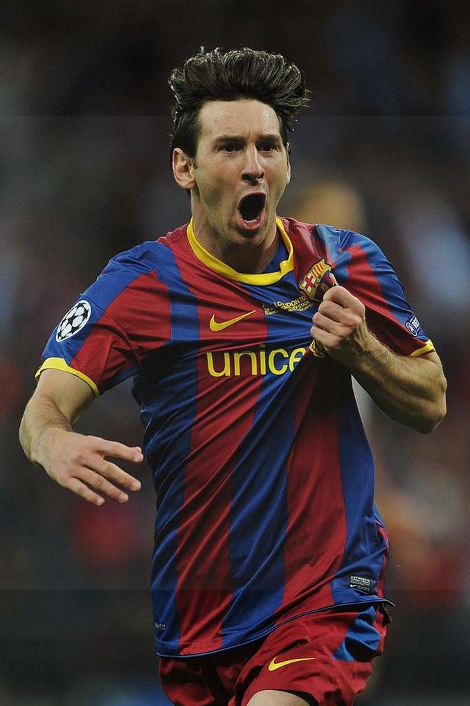 A soccer player in a Retro1999 Barcelona 2010-11 Home Shirt celebrates on the pitch, his hand clutching the club badge—a passionate moment any fan will treasure.