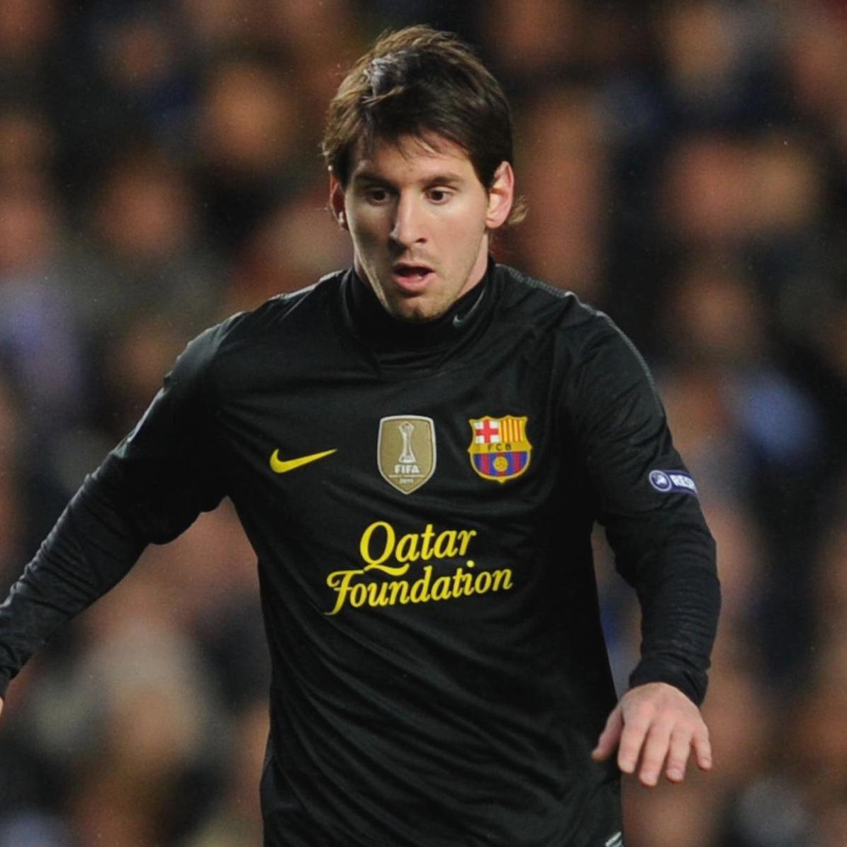A soccer player in a Retro1999 Barcelona 2011-12 Away Shirt with Qatar Foundation sponsor is running on the field during a match, with blurred spectators in the background.
