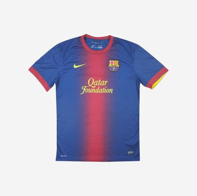 The Retro1999 Barcelona 2012-13 Home Shirt features a blue base with a red gradient stripe, yellow Nike logo, club crest, and Qatar Foundation sponsor. Red collar and sleeve trim with yellow detail add retro flair inspired by past La Liga victories.
