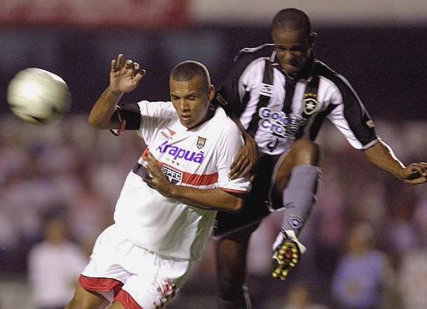 Two soccer players battle for possession—one in white, the other in the iconic Retro1999 Botafogo 1999-00 Home Shirt, celebrating the classic look of the famed Brazilian football club.