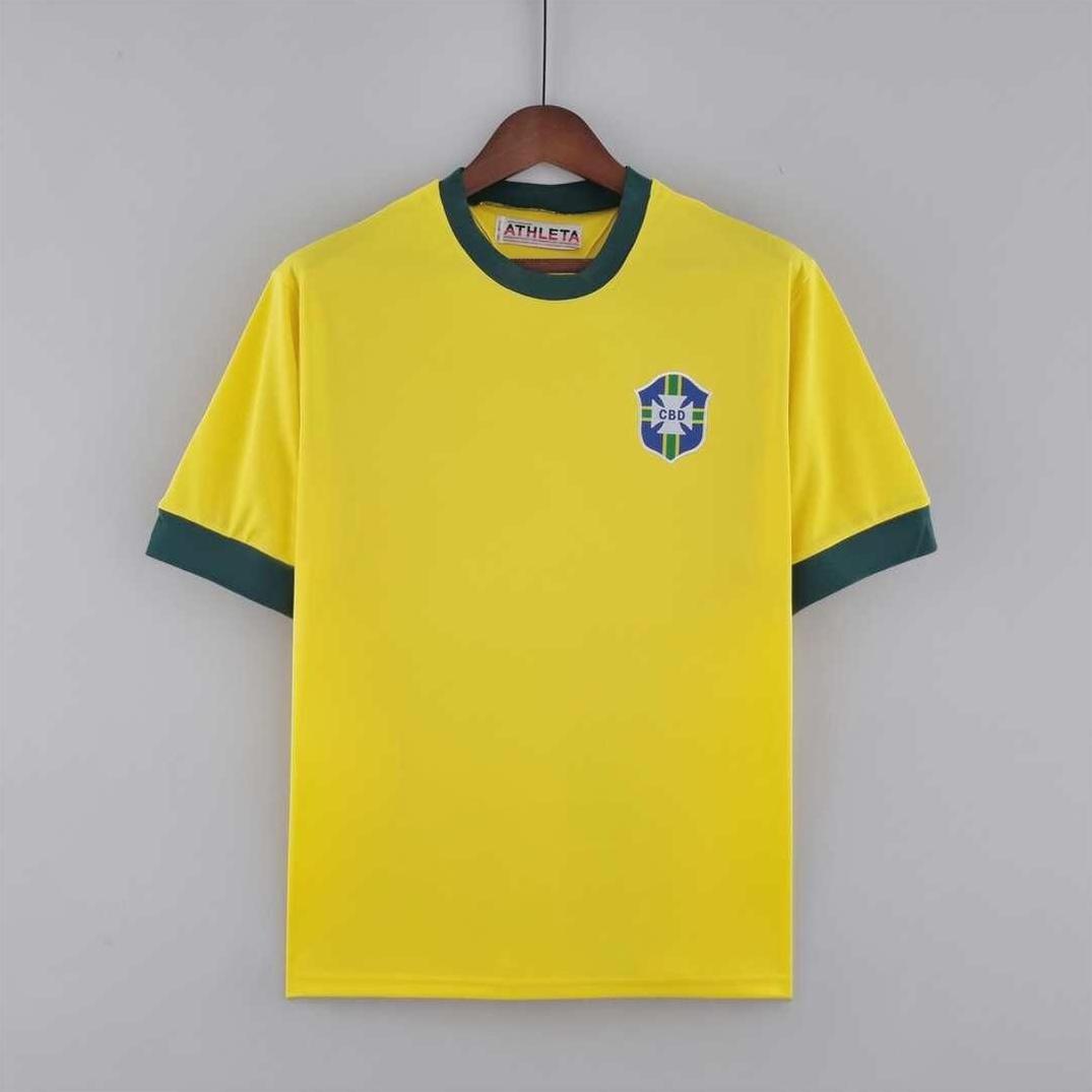 The Retro1999 Brazil 1970 Home Shirt is a yellow short-sleeve soccer jersey with green collar and cuffs, blue left chest badge, inspired by the iconic original—ideal for football fans and shown on a wooden hanger against a gray background.