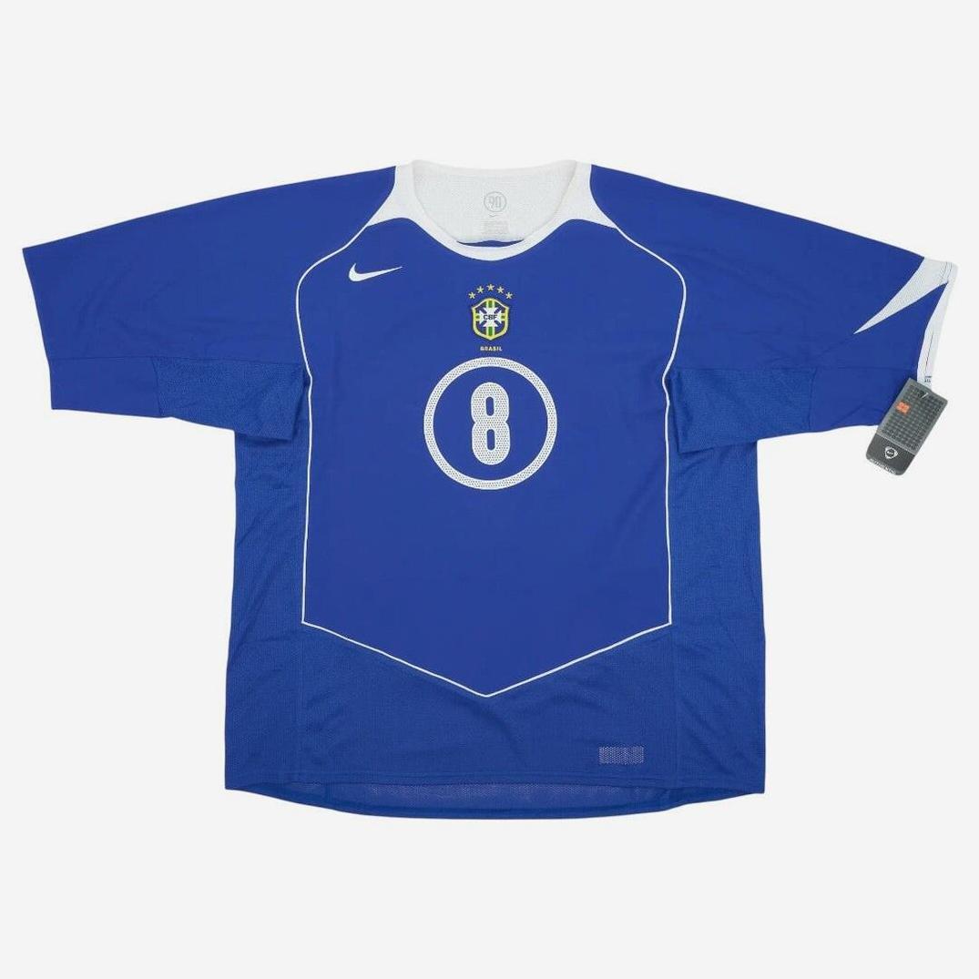 The Retro1999 Brazil 2004 Away Shirt features blue fabric with white trim, number 8, Nike logo, and Brazil crest—ideal for national team fans and retro kit collectors. Includes tag attached to the right sleeve.