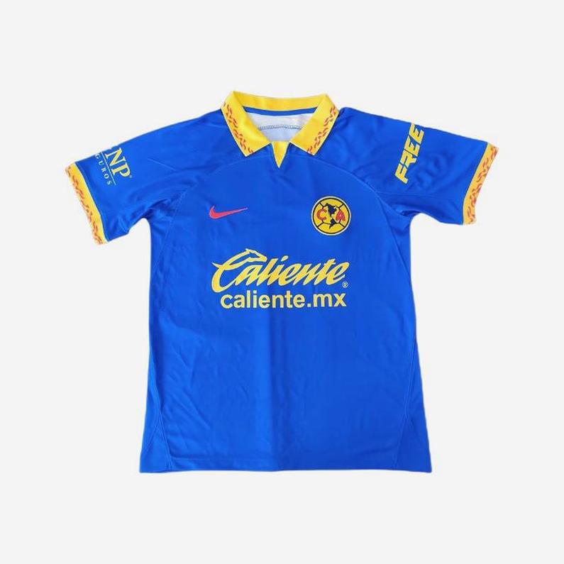 Show your team spirit with the CF America 2023-24 Away Shirt by Retro1999, featuring blue fabric, yellow collar and trim, the club crest on the chest, and sponsor logos including Caliente.mx in yellow and white on the front.