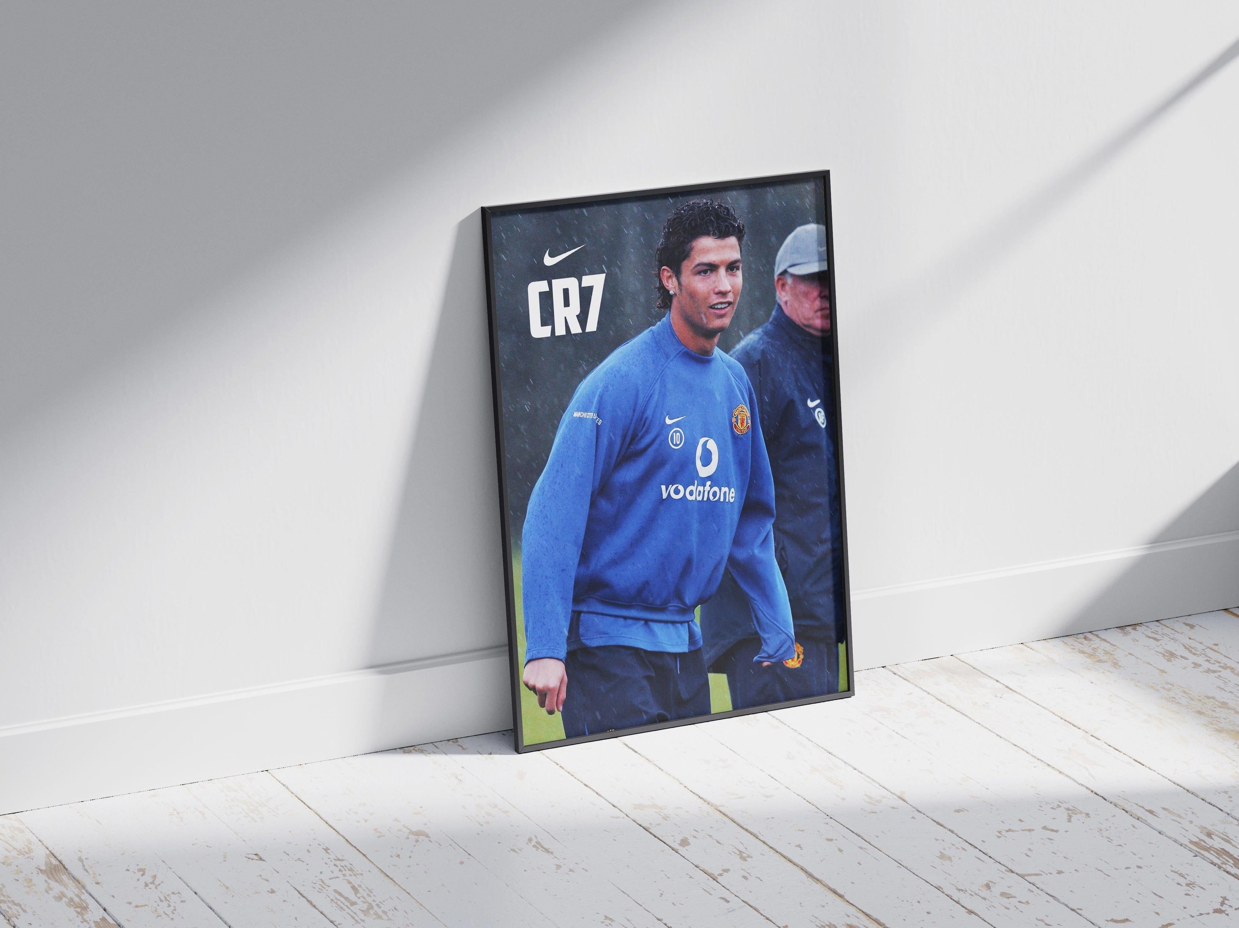 The Retro1999 CR7 x Sir Alex Poster shows a young footballer in a blue Vodafone sweatshirt leaning against a white wall, with CR7 and Nike logos above—a tribute to Manchester United history—while sunlight streams in, another figure stands behind.