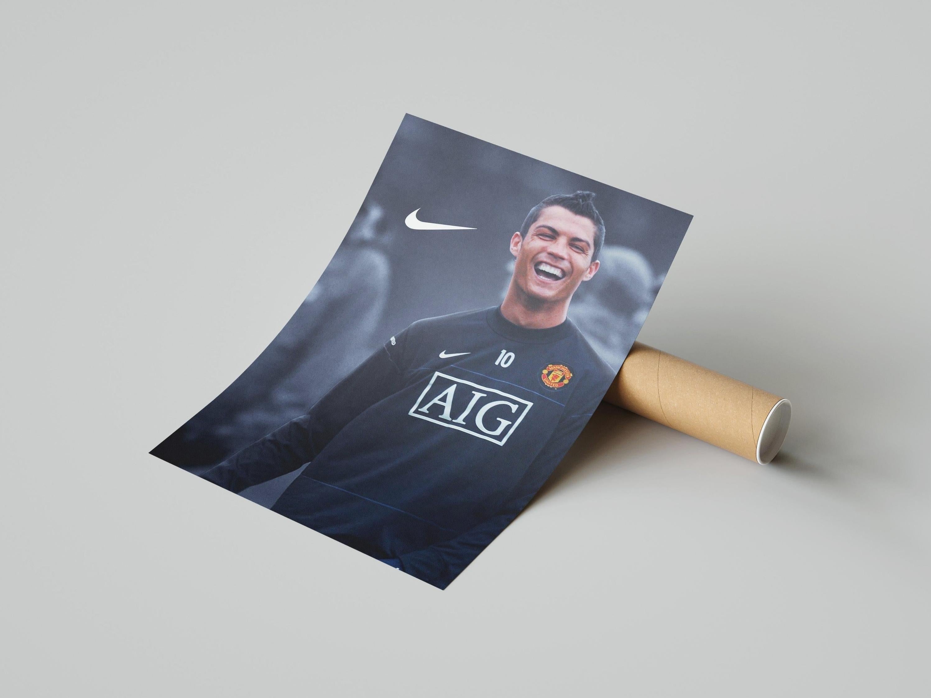 The Retro1999 Cristiano Ronaldo Manchester United Poster shows Ronaldo smiling in a dark jersey with “AIG” and Nike logos on a gray background—ideal football wall art for fans.