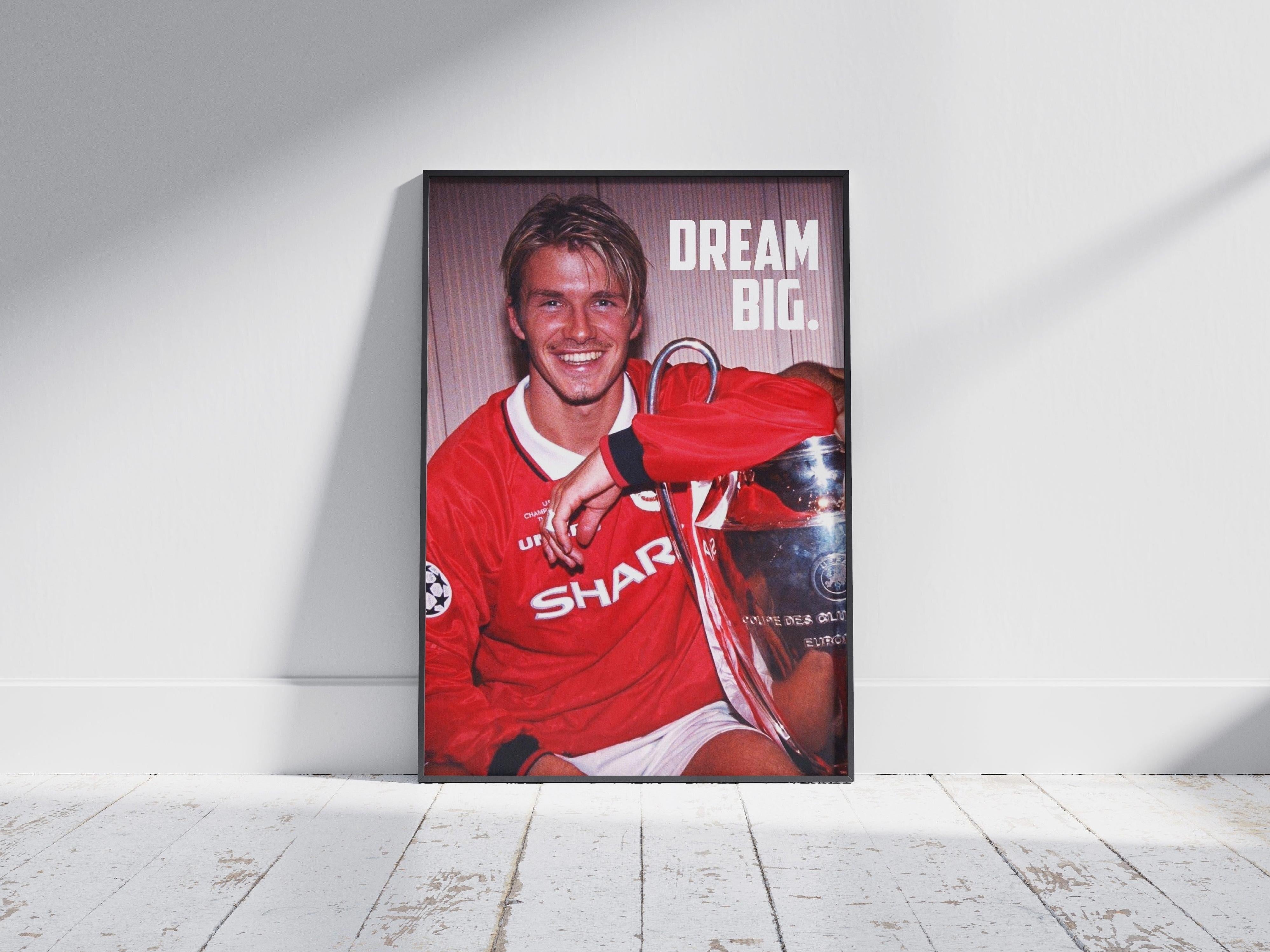 The Retro1999 David Beckham Dream Big Poster features the soccer star in a red jersey, smiling with a trophy and bold DREAM BIG. text—a stylish, framed decor piece for any football fan’s space.