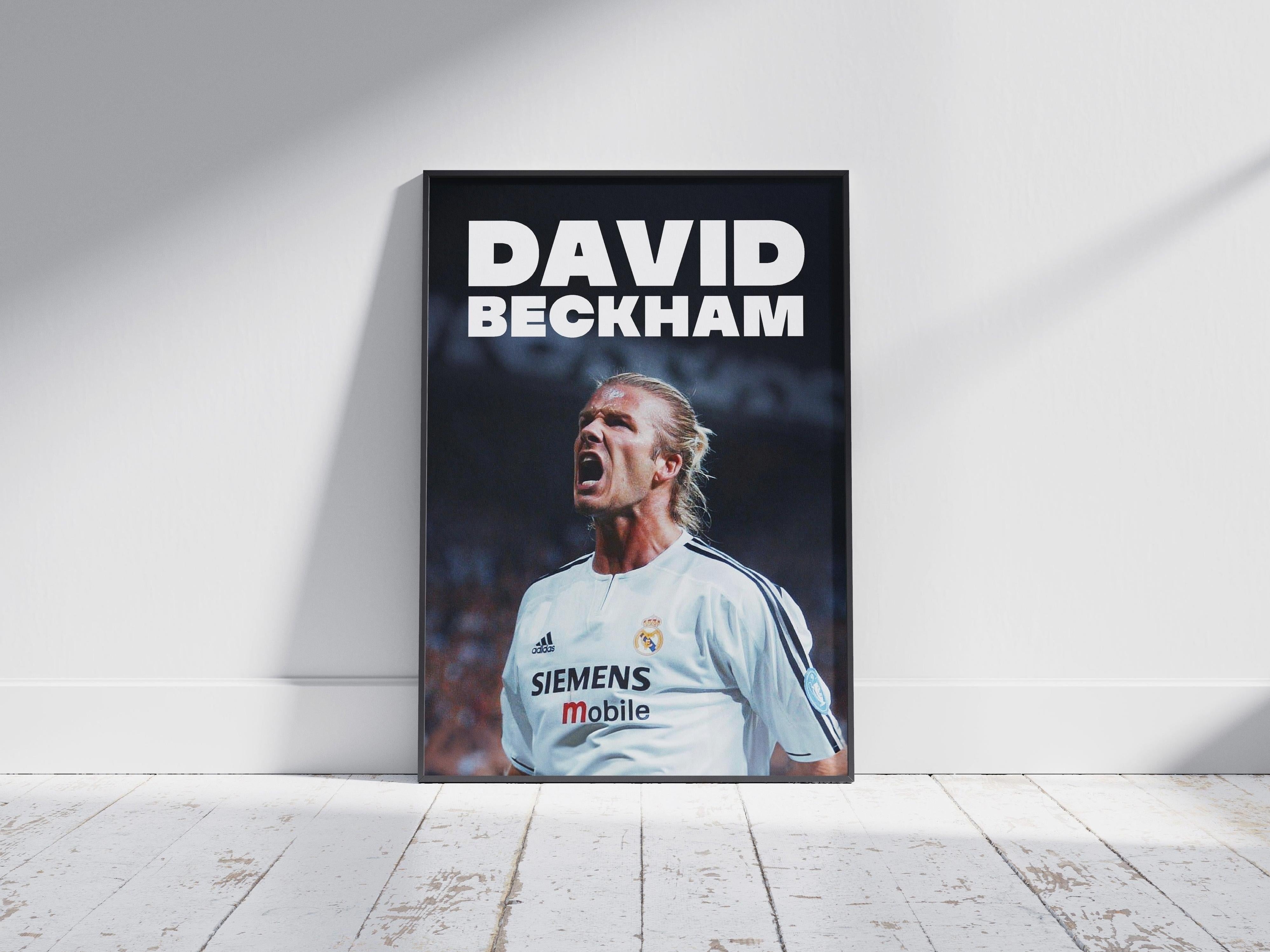 The Retro1999 David Beckham x Real Madrid Poster features the football legend in a white jersey, shouting with passion. Displayed on a wooden floor against a soft background, it’s a bold tribute to Beckham’s iconic era at Real Madrid.