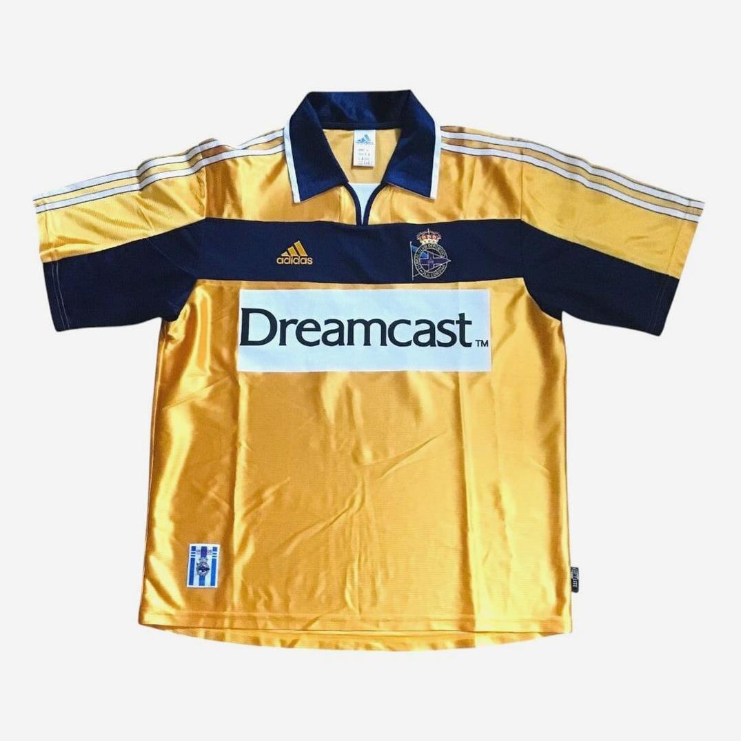Retro1999’s Deportivo 2000-01 Away Shirt features yellow and navy colors, classic white stripes, “Dreamcast” on the front, and a club crest—a stylish pick for football fans.