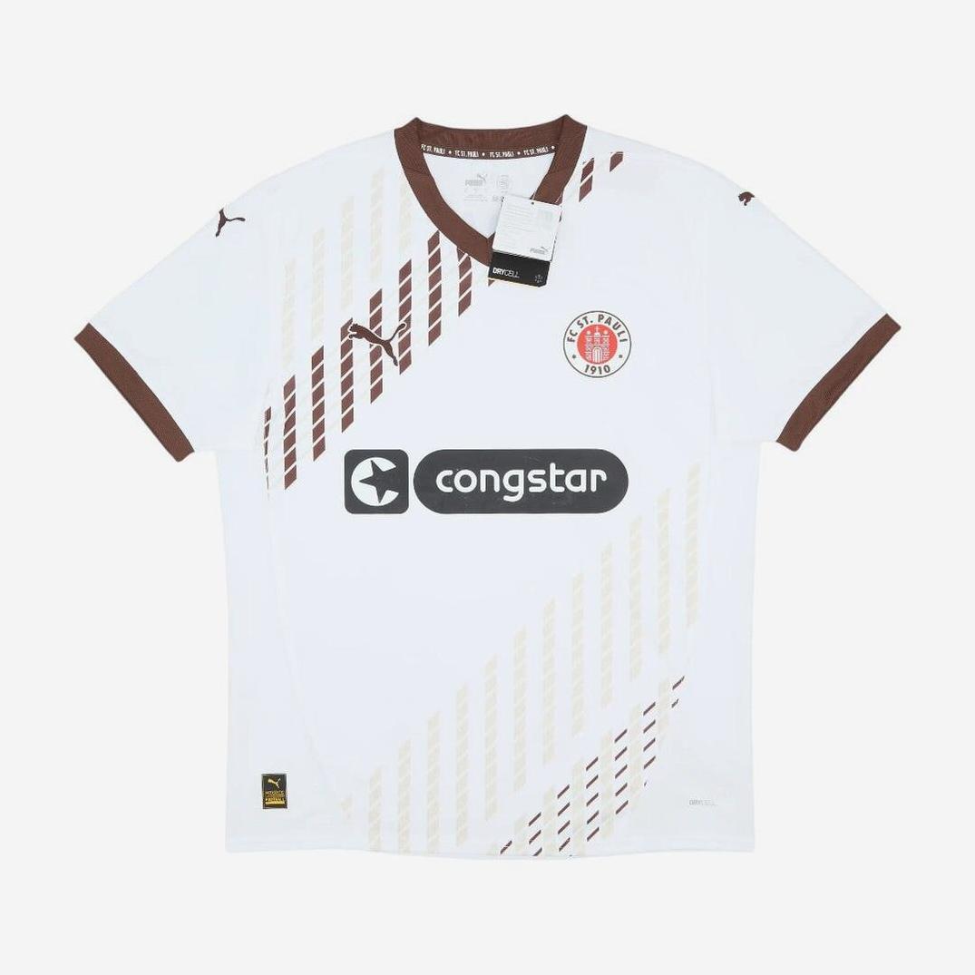 The Retro1999 FC St. Pauli 2024-25 Away Shirt features a white design with brown diagonal stripes, retro style, brown collar and sleeve edges, club crest, Congstar sponsor, and tags on the collar—ideal for Bundesliga fans.