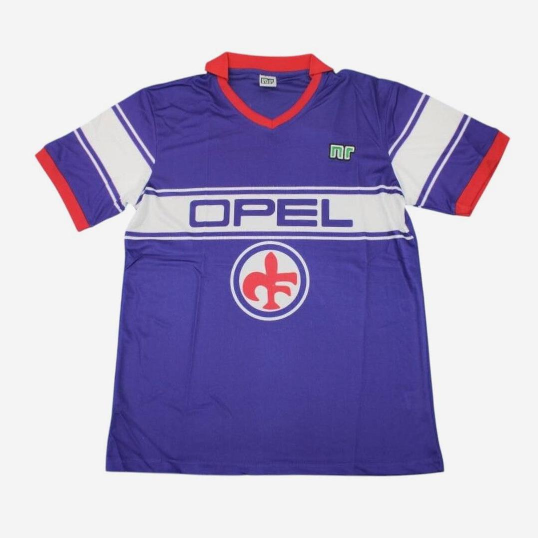 The Retro1999 Fiorentina 1984-85 Away Shirt is purple with a red collar and cuffs, white chest stripes, bold “OPEL” lettering, a red fleur-de-lis logo beneath it, and a small green emblem on the right chest.