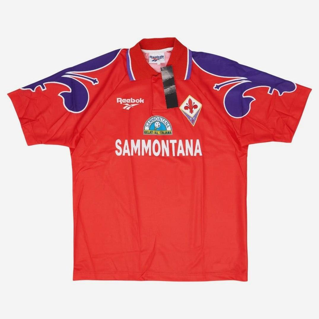 The Retro1999 Fiorentina 1995-96 Third Shirt features a red base, purple and white shoulder designs, Reebok logo, Fiorentina crest, Sammontana sponsor, and black collar tag—a must-have retro kit for Serie A fans.