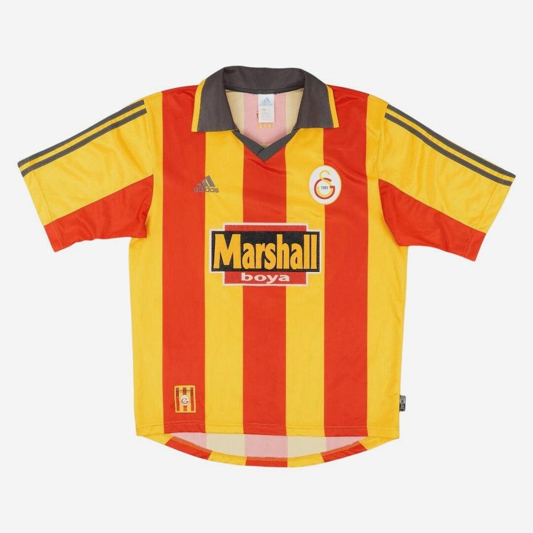 The Retro1999 Galatasaray S.K. 1999-00 Home Shirt features yellow and red vertical stripes, gray collar and sleeve trim, the Marshall boya sponsor logo, and a circular G crest—ideal for fans seeking an iconic football jersey.