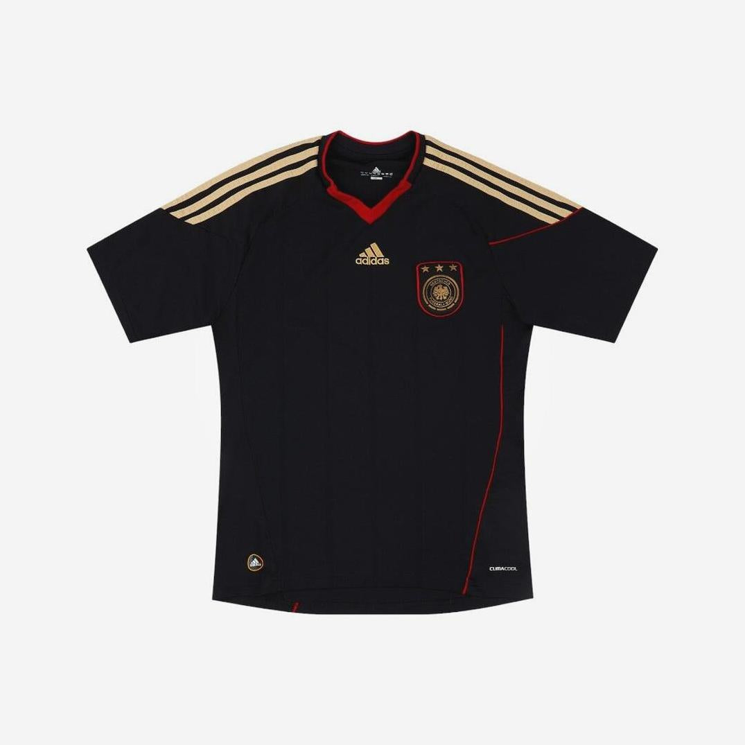 The Retro1999 Germany 2010 Away Shirt features a black design with gold Adidas logo, three gold shoulder stripes, gold team crest with three stars on the chest, and red trim on the collar and sides.