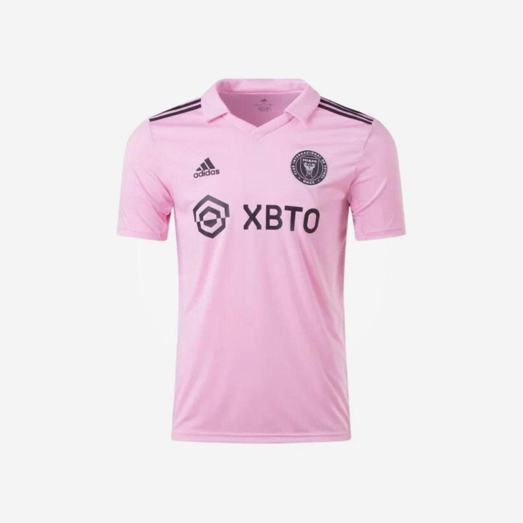The Retro1999 Inter Miami 2023/24 Home Shirt is light pink with black accents, featuring the Inter Miami CF crest, Adidas logo, and XBTO sponsor. This MLS jersey has a classic collar and short sleeves—ideal for Lionel Messi fans.