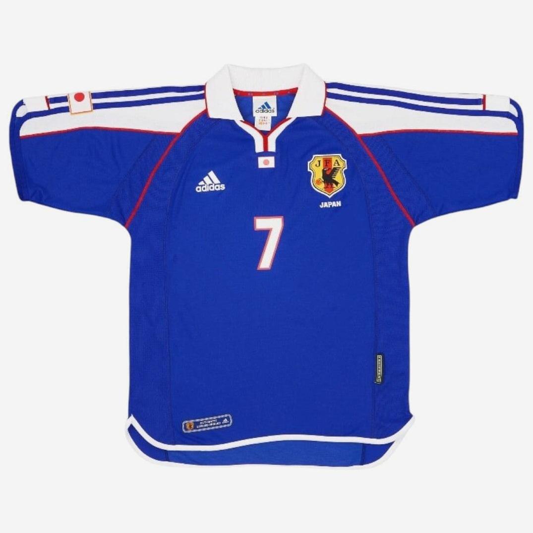 The Japan 2000 Home Shirt by Retro1999 features blue with white and red accents, number 7 on the front, Adidas logo, Japan team crest on the chest, and a Japanese flag on the left sleeve—a classic piece of Japanese football history.