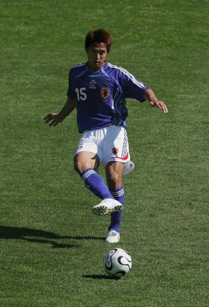 Wearing the Retro1999 Japan 2006 Home Shirt with number 15, a soccer player readies to kick a classic black and white ball on green grass—a standout moment inspired by Japanese football tradition.