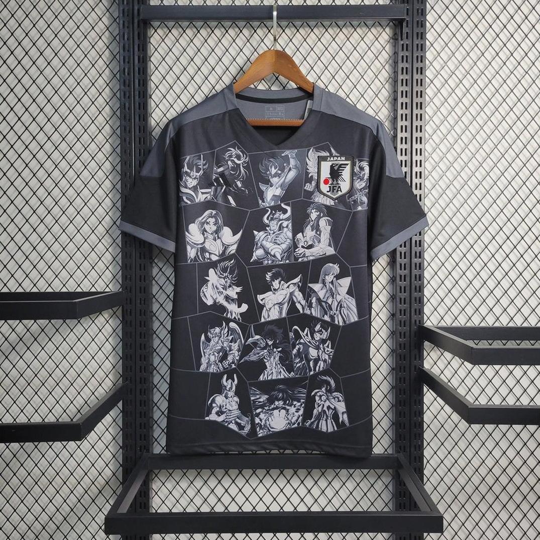 The Retro1999 Japan 2023 Anime Saint black t-shirt features Japan’s football crest and white manga-style anime graphics on the front, shown hanging on a wooden hanger against a metal mesh background.