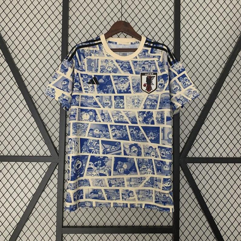 The Japan 2023 Special Edition jersey by Retro1999 features blue and white manga-style comic panels, displayed on a wooden hanger against a black metal grid—a striking retro kit for fans.