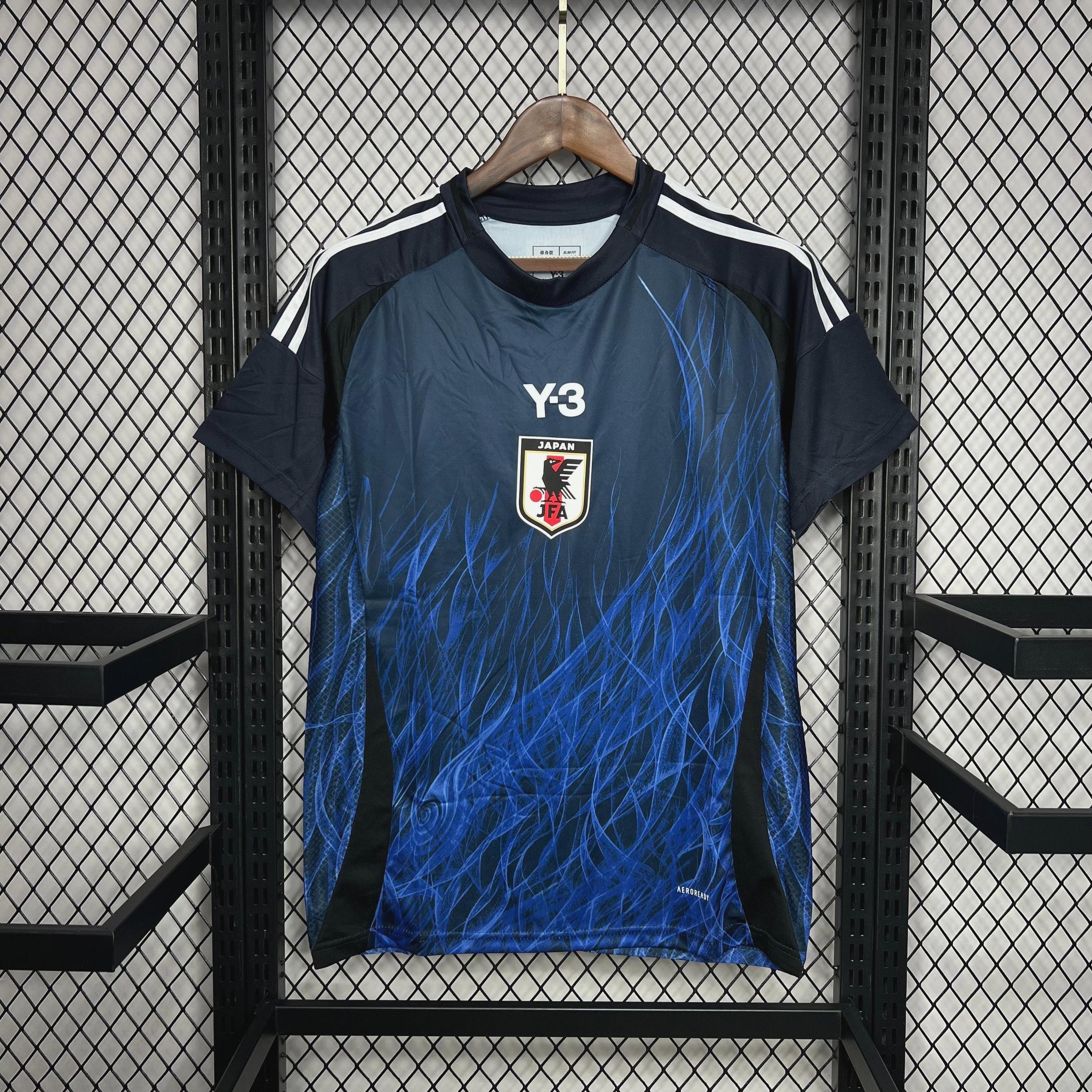 The Japan 2024 Special Edition jersey by Retro1999 features a dark blue design with white shoulder stripes, a swirling blue pattern, and Japan’s crest—exclusive national team merchandise on a wooden hanger against black mesh.