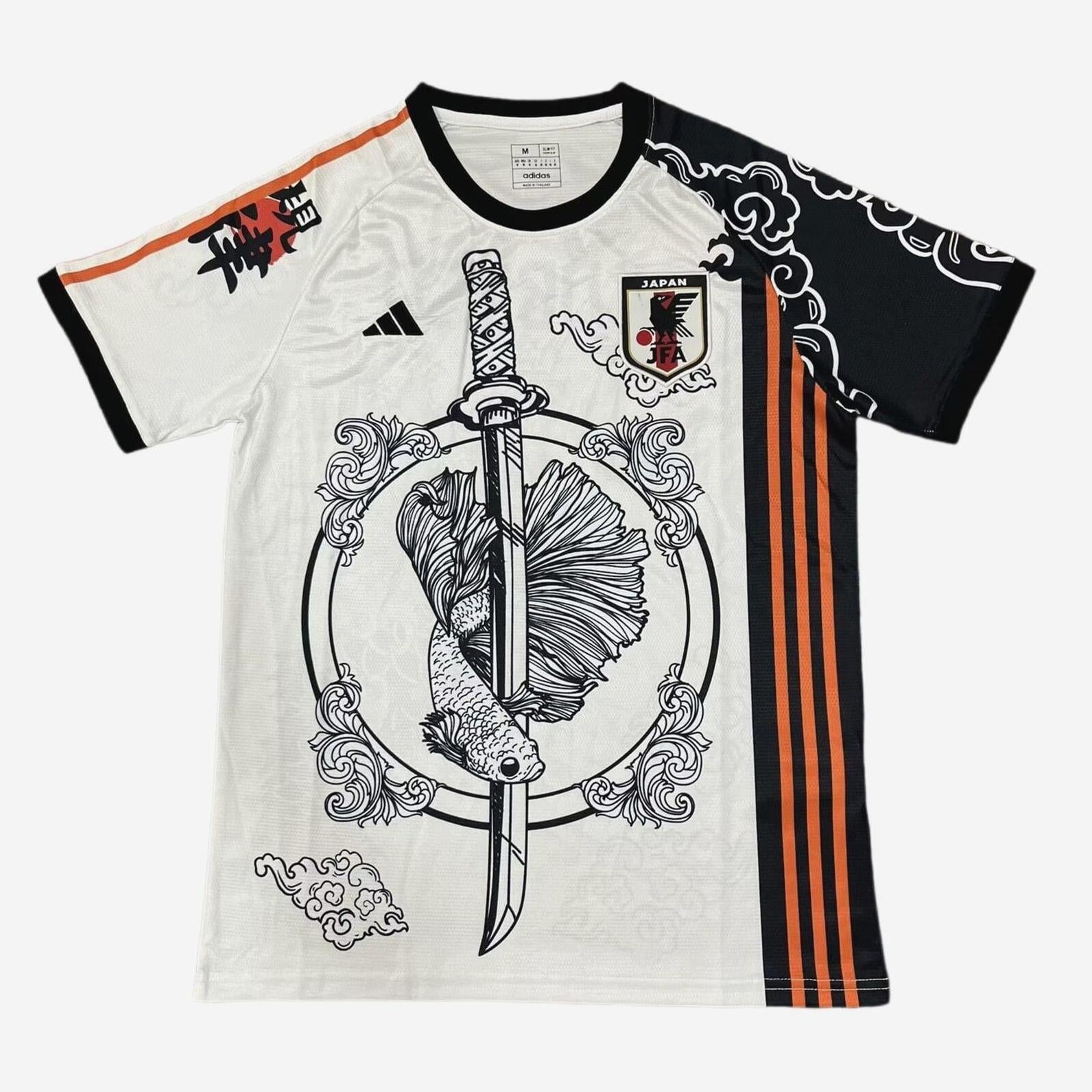The Retro1999 Japan 2024 Tsubasa Shirt is a white and black soccer jersey with orange stripes, featuring a sword with a fish, ornate cloud designs, and the Japan national team crest on the chest.