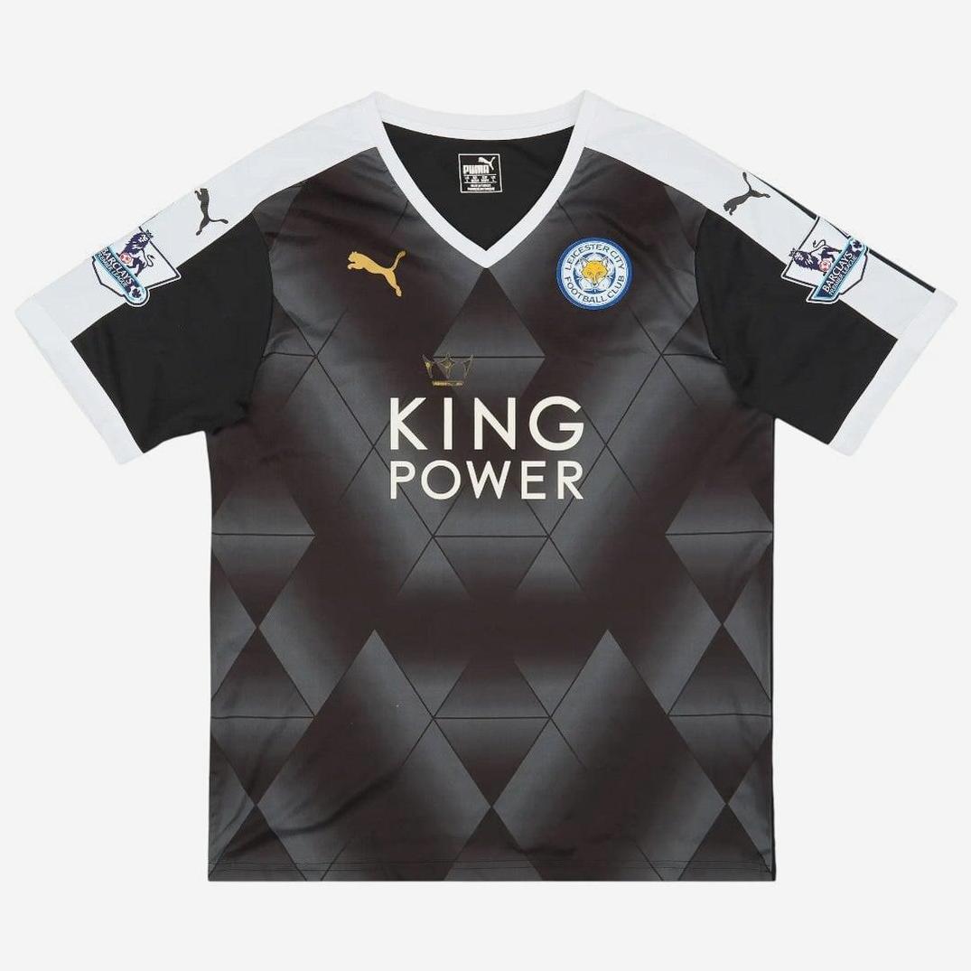 The Leicester City 2015-16 Away Shirt by Retro1999 features black and dark grey with a diamond pattern, white shoulders, gold logo, club badge, KING POWER sponsor, and Premier League sleeve patches—a classic retro kit.
