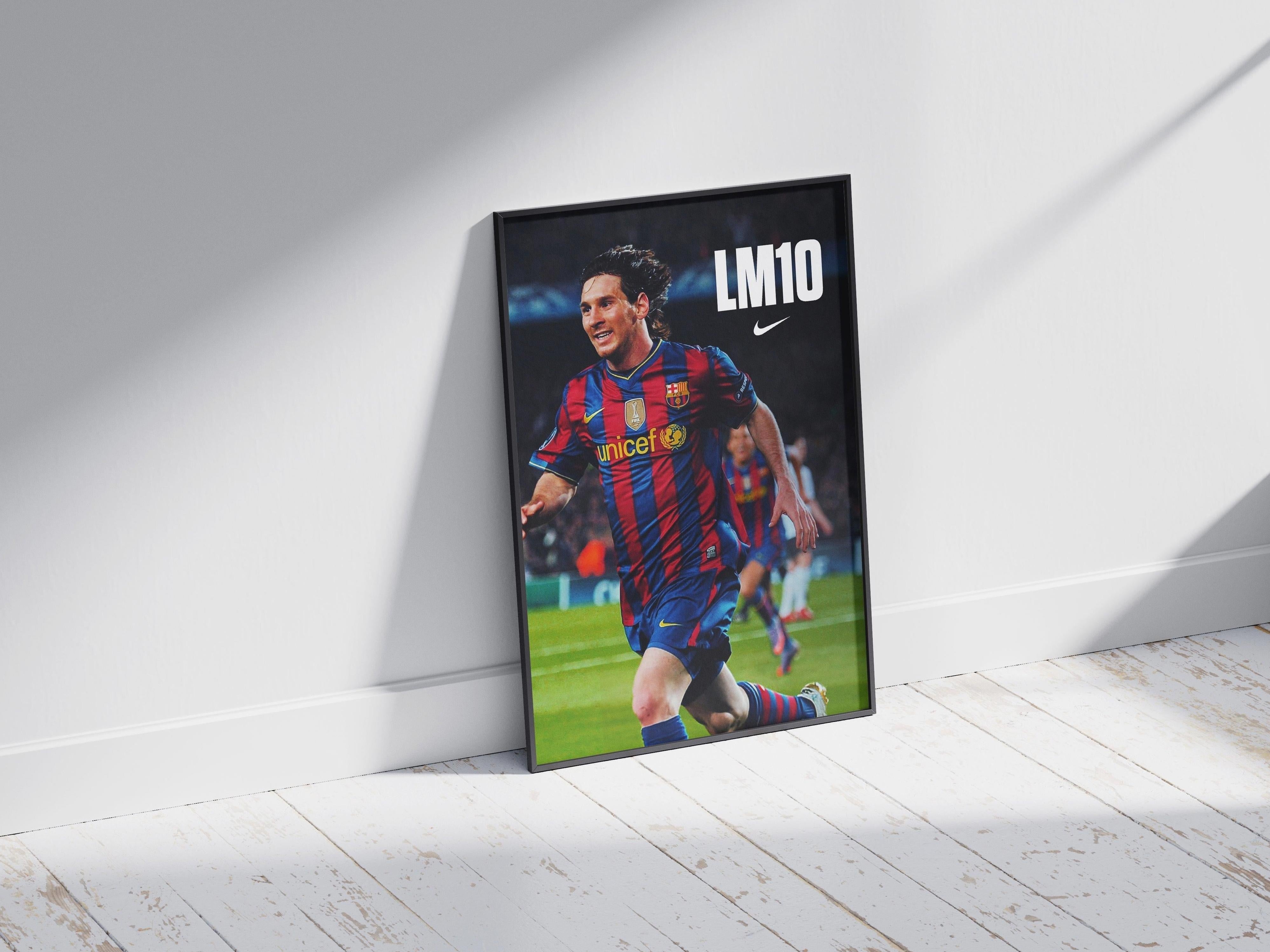 A Retro1999 Lionel Messi LM10 Poster, featuring him in a Barcelona jersey with the LM10 and Nike logos, is framed and leaning against a white wall as sunlight casts shadows on the wooden floor.