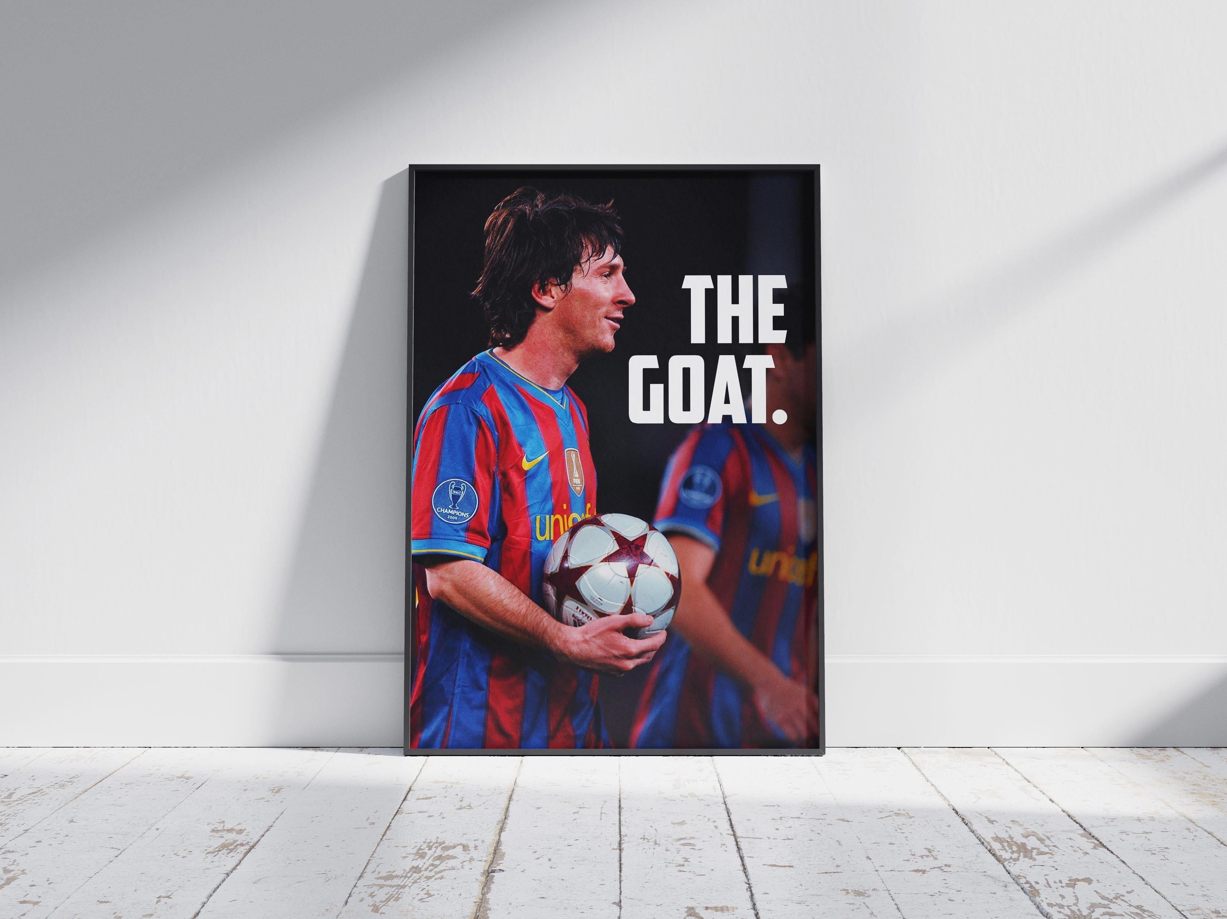 The Retro1999 Lionel Messi MOTM Poster shows the soccer icon in a red and blue jersey with THE GOAT in bold white text. Perfect for football fans, it comes framed and stands on a white wooden floor against a plain wall.