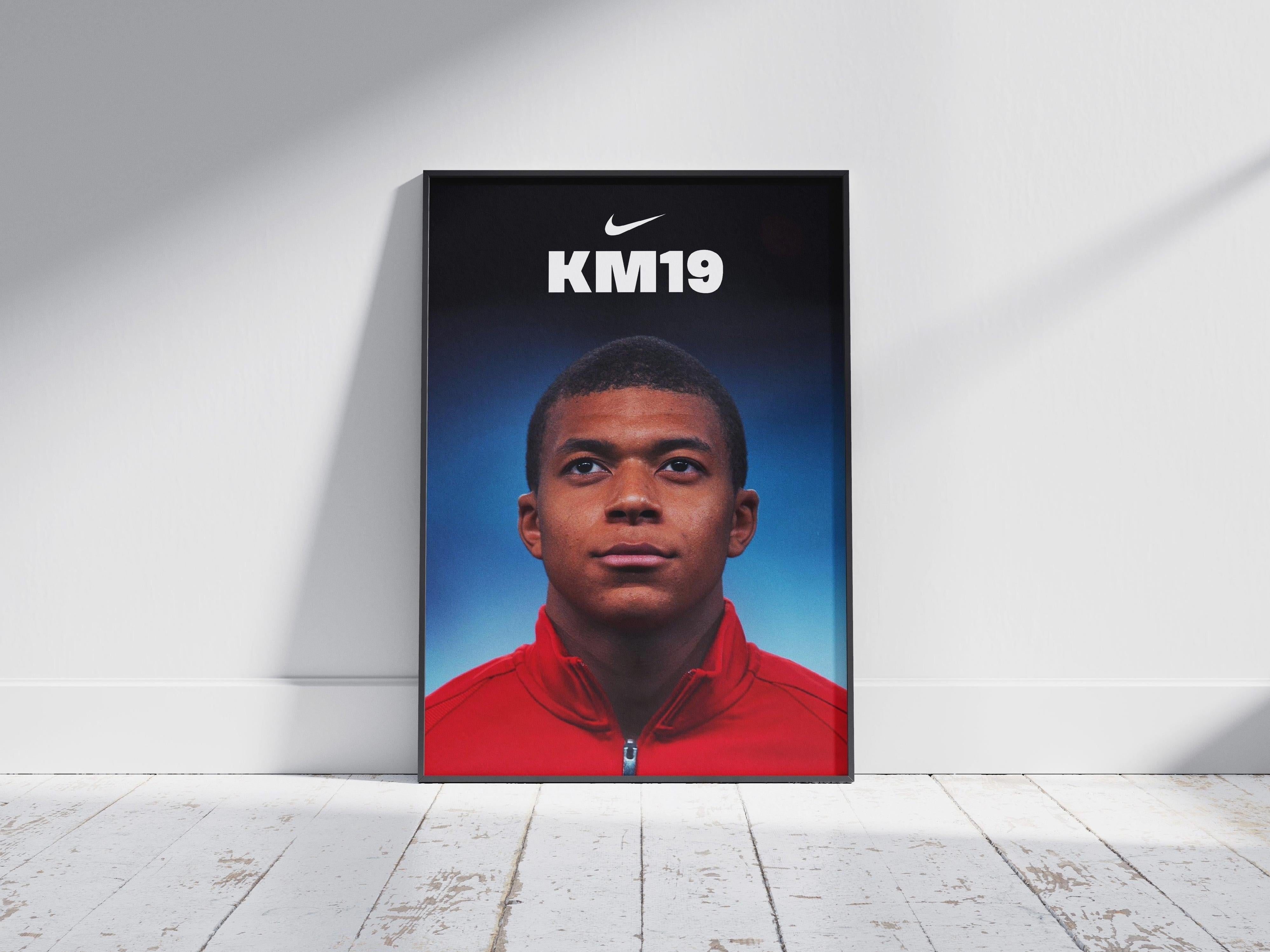 The Mbappe x AS Monaco Poster by Retro1999 features the young star in a red jacket with a serious look, Nike logo, and KM19 text above his head, leaning against a white wall on a wooden floor—celebrating his AS Monaco era.