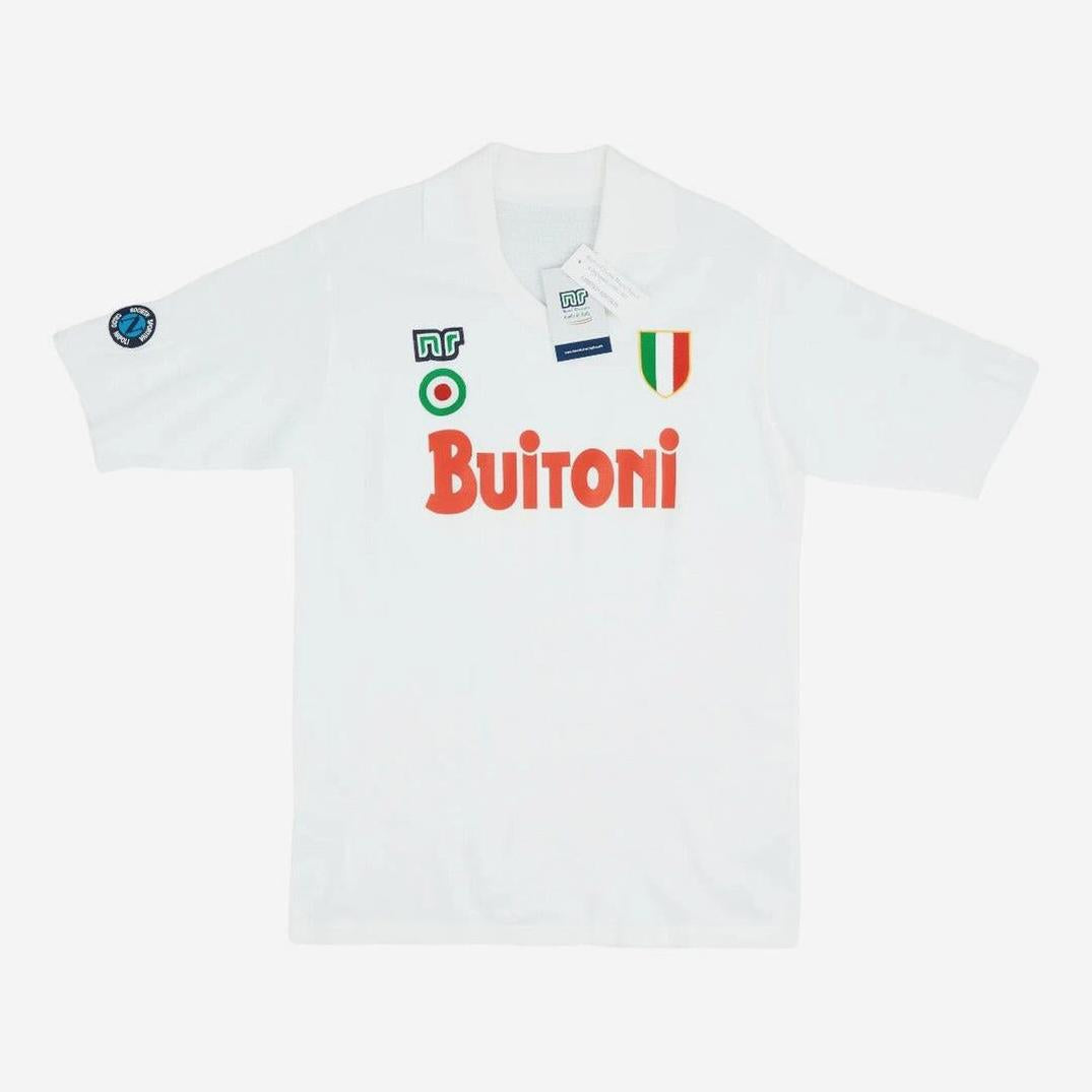 The Retro1999 Napoli 1987-88 Away Shirt features a white design with red Buitoni text, green and red patches, an Italian flag shield, and blue sleeve emblem. This vintage kit is displayed on a plain white background with tags attached.