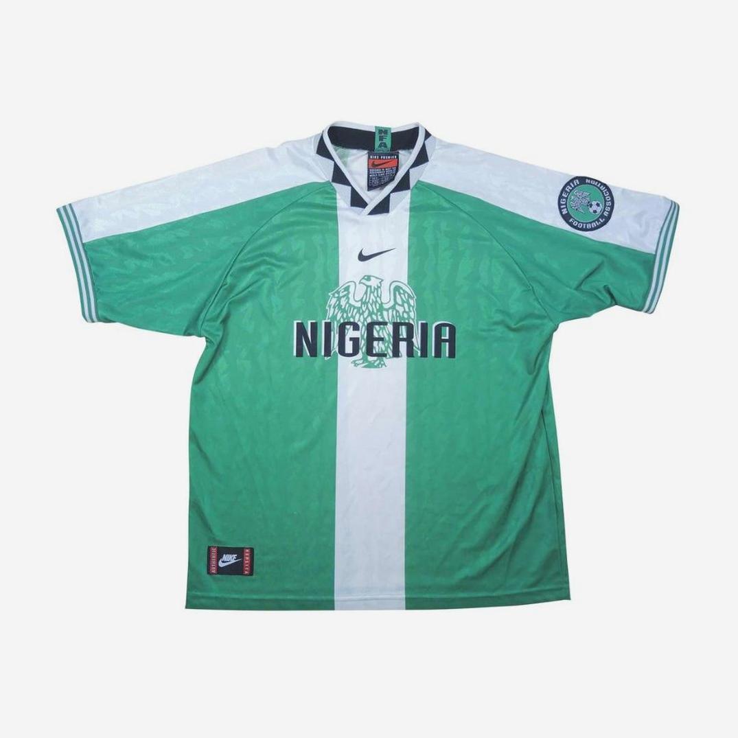 The Retro1999 Nigeria 1996 Home Shirt features a green and white design with an eagle emblem, Nike logo, NIGERIA text, short sleeves, and a left sleeve badge—paying tribute to the classic Super Eagles jersey.