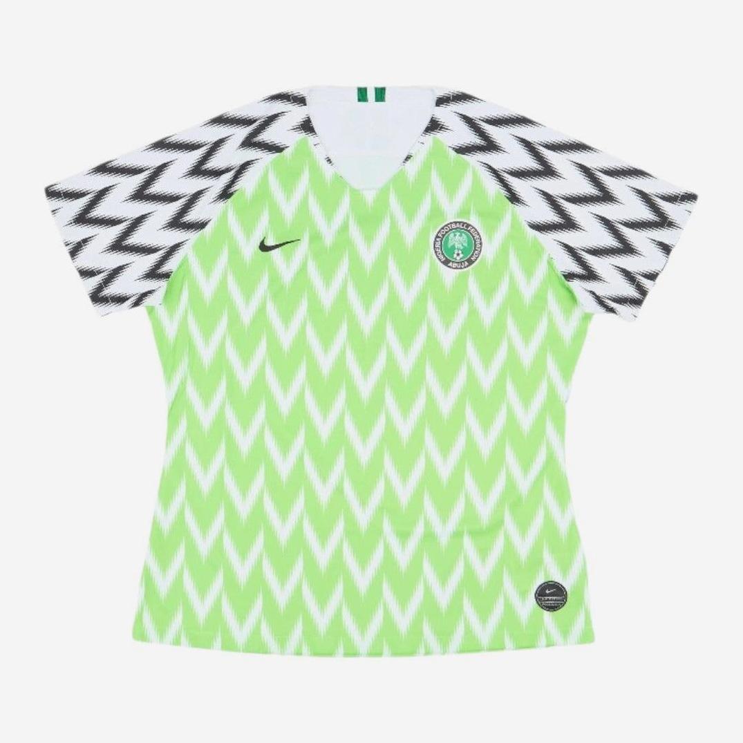 The Nigeria 2018 Home Shirt by Retro1999 features the iconic green and white zigzag design, with a black logo and national team crest—a classic retro kit.