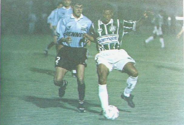 Two soccer players vie for the ball under stadium lights; one wears the iconic Retro1999 Palmeiras 1996 Home Shirt, while the other is in a light jersey and black shorts—capturing a memorable football moment.