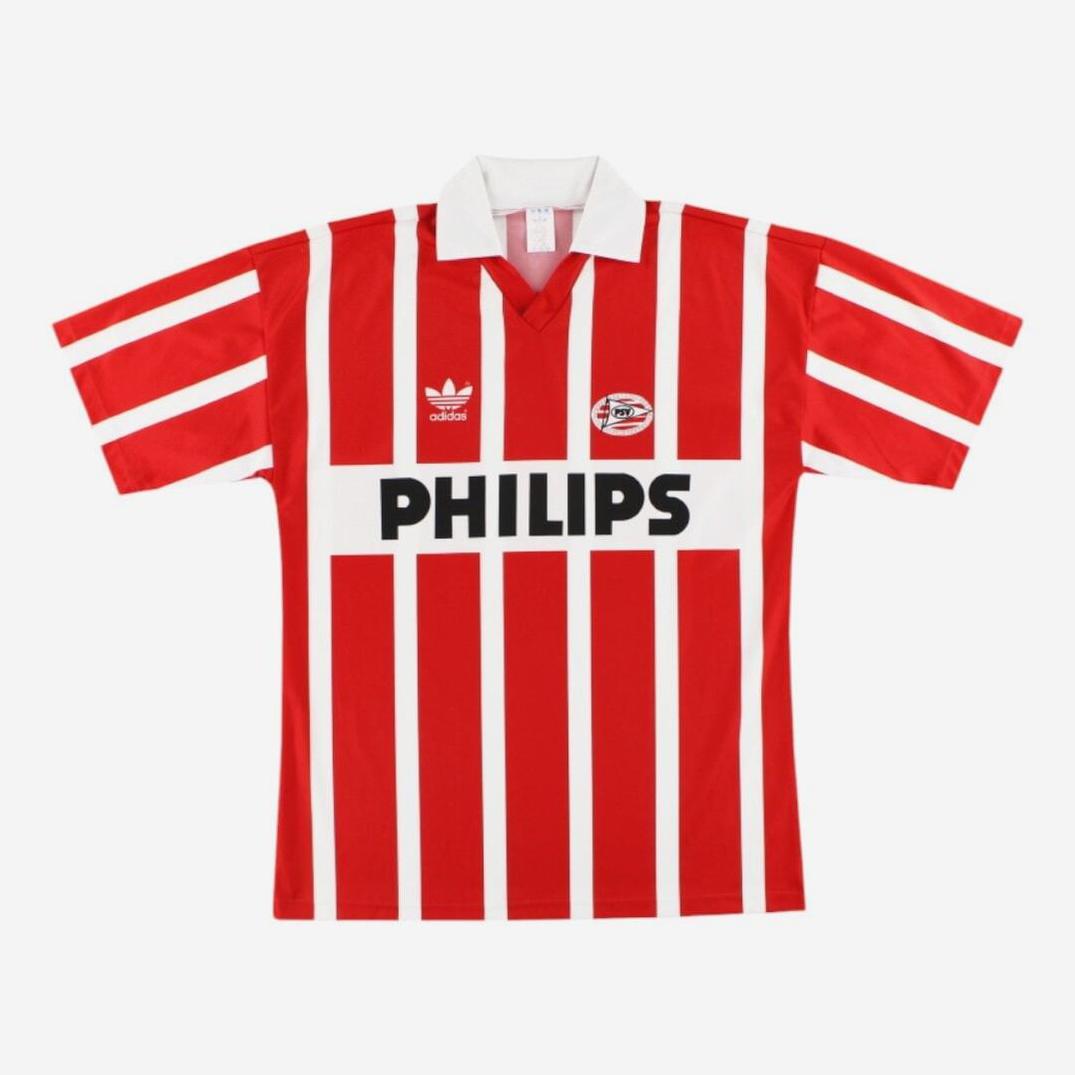 The PSV 1990-91 Home Shirt by Retro1999 features red and white vertical stripes, a white collar, club badge, Adidas logo, and black “PHILIPS” sponsor—a classic retro kit from the iconic 1990-91 season.