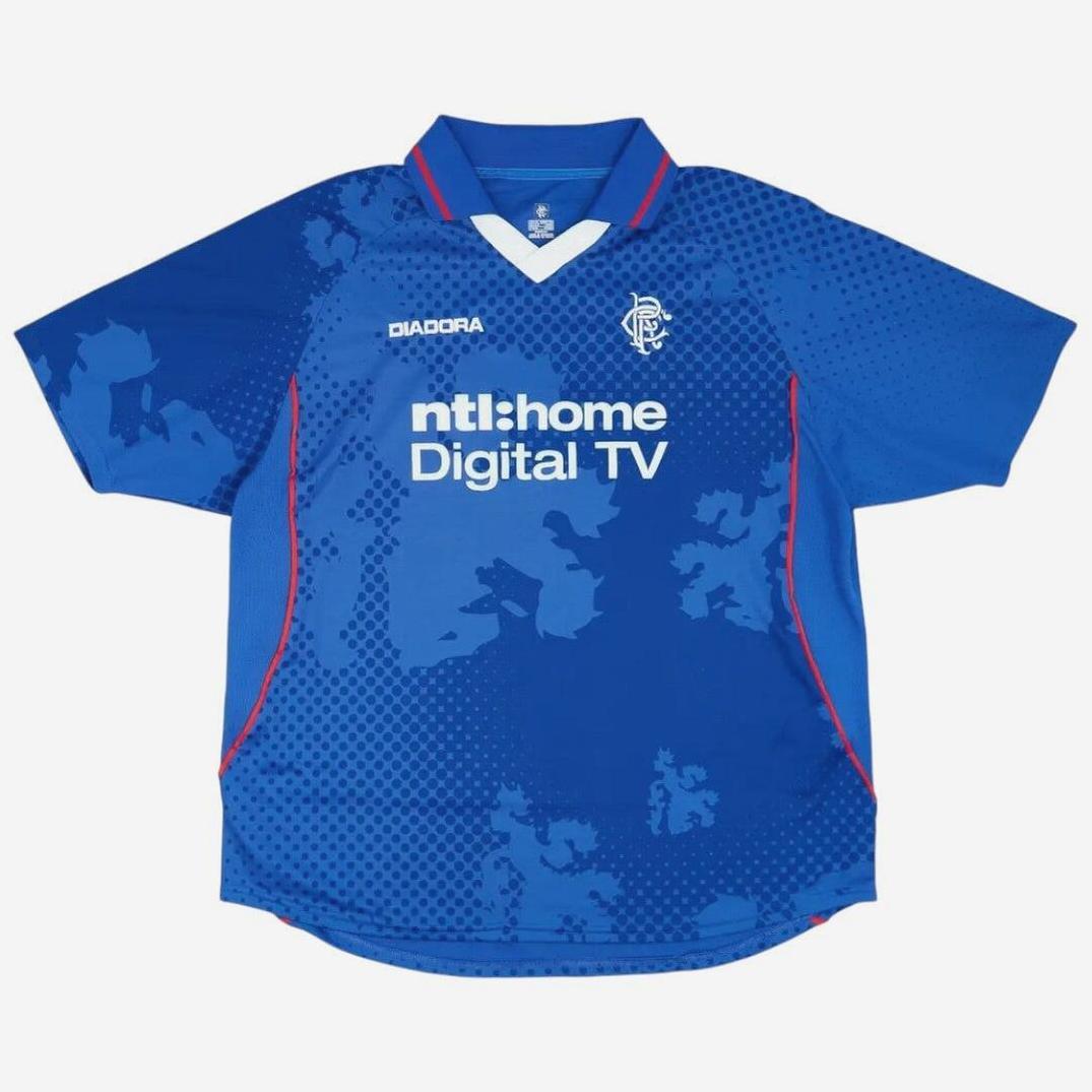 The Retro1999 Rangers F.C. 2002-03 Home Shirt is a blue jersey with red accents, the Rangers crest, and ntl:home Digital TV sponsor—an iconic replica set against a white background.