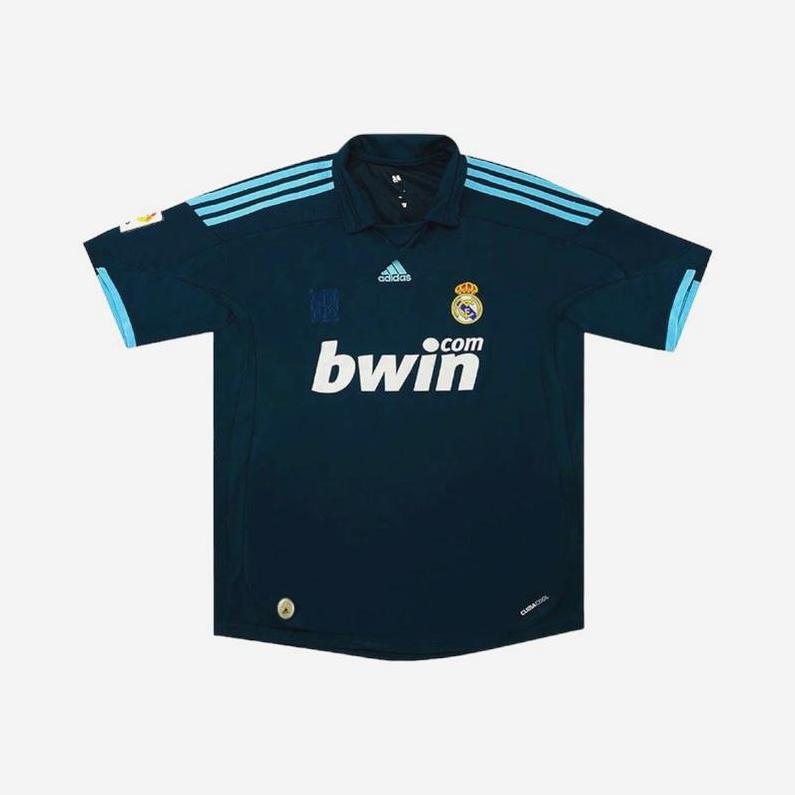 The Retro1999 Real Madrid 2009-10 Away Shirt features a dark blue design with light blue shoulder stripes, Adidas logo, Bwin sponsor, and club crest on the chest—ideal for fans and shown on a plain white background.
