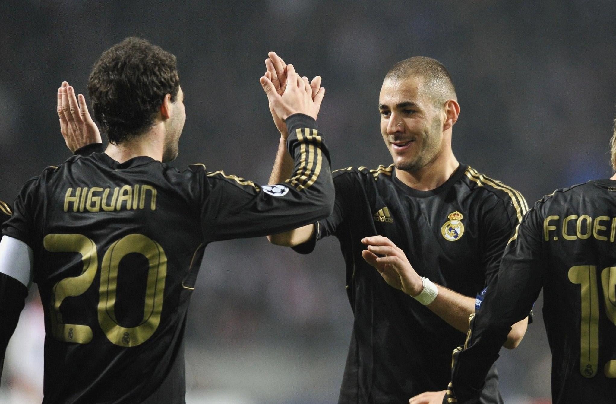 Two players in Retro1999s Real Madrid 2011-12 Away Shirts—one with Higuain 20, the other smiling—high-five during a match, while another teammate celebrates on the right.