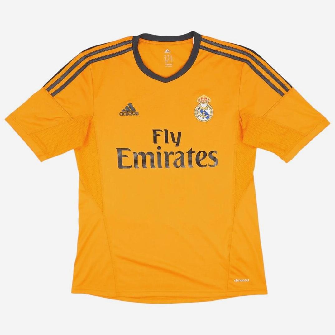 The Retro1999 Real Madrid 2013-14 Third Shirt features orange fabric, black Adidas shoulder stripes, the club crest, Adidas logo, and Fly Emirates sponsor—an iconic retro kit for fans of classic La Liga seasons.