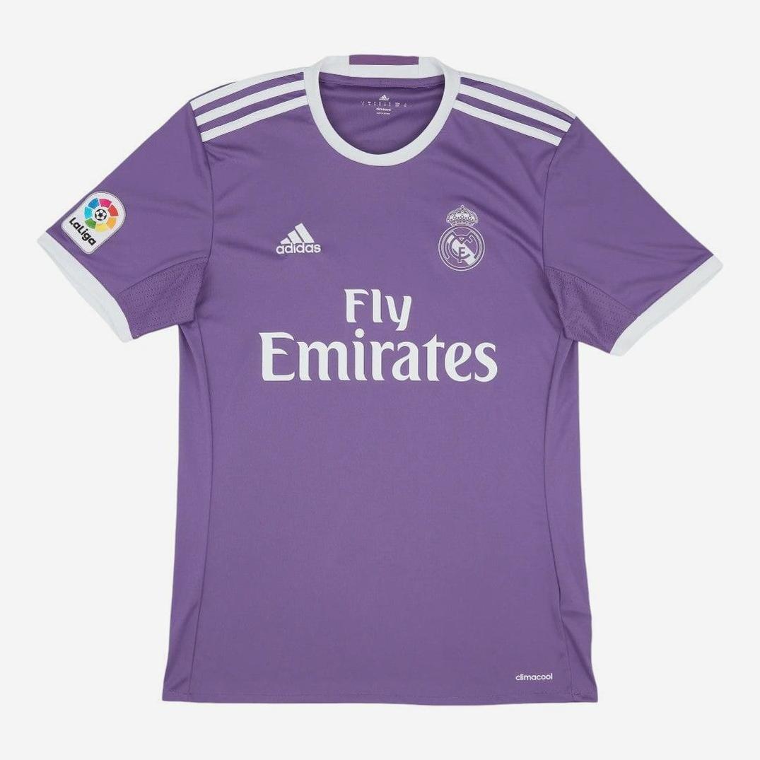The Real Madrid 2016-17 Away Shirt by Retro1999 is a purple kit with white trim, featuring the club crest, Adidas logo, Fly Emirates sponsor on the front, and La Liga patch on the right sleeve—an iconic retro piece for fans.