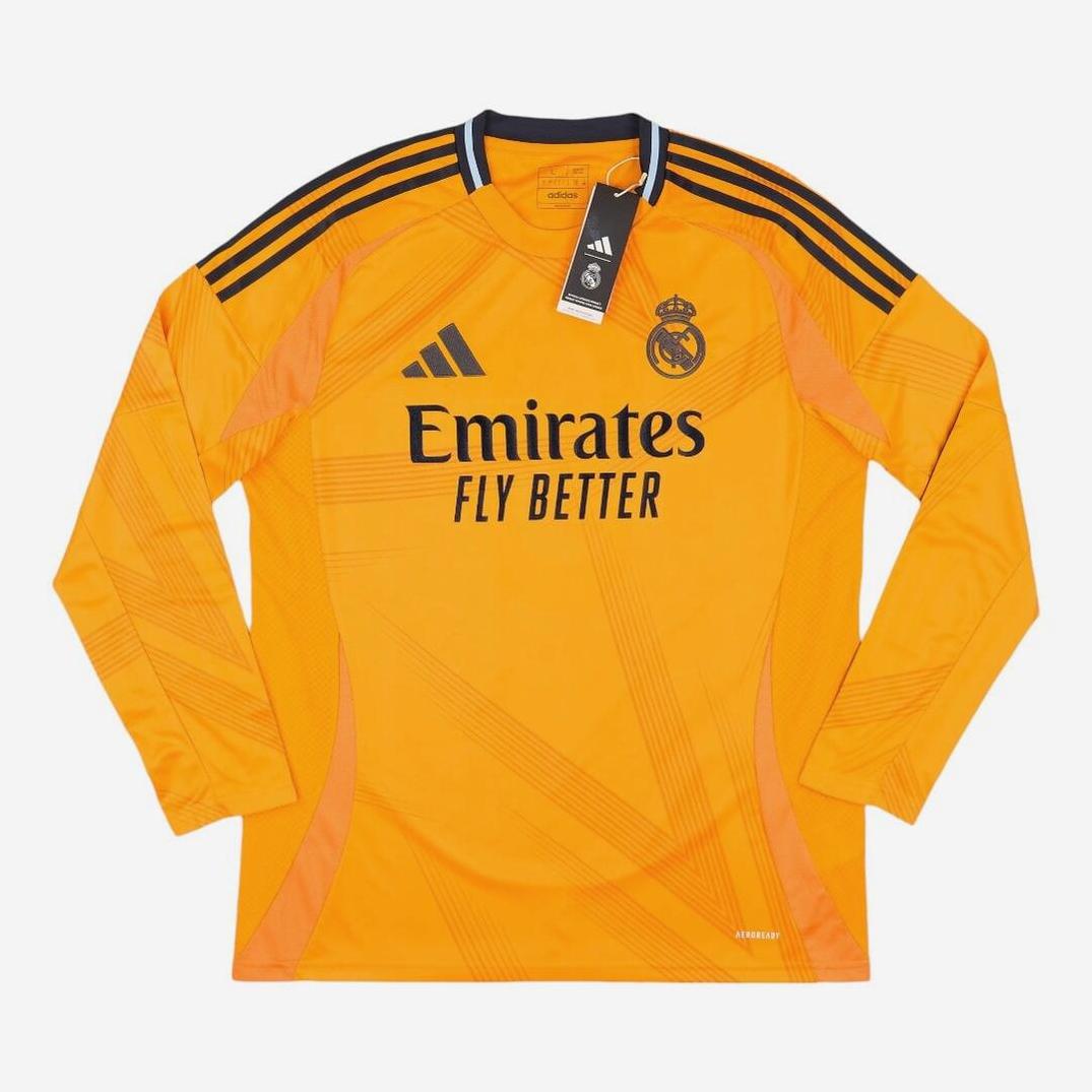 The Real Madrid 2024-25 Longsleeve Away Shirt by Retro1999 is orange with black Adidas stripes, club crest, and Emirates Fly Better sponsor on the front. Includes collar tag—ideal for La Liga fans.