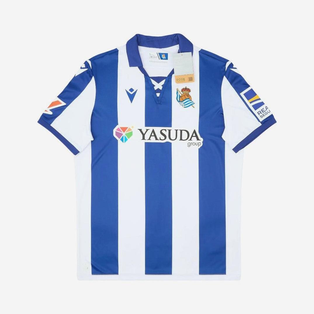 The Retro1999 Real Sociedad 2024-25 Home Shirt features blue and white vertical stripes, a collar, club badge, Yasuda Group sponsor logo, and sleeve patches—a stylish retro-inspired kit for dedicated La Liga fans.