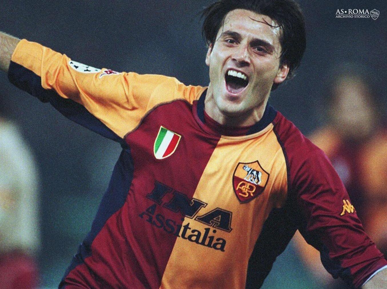 A soccer player celebrates joyfully in the Retro1999 Roma 2001-02 Home Shirt, arms outstretched and mouth open. This classic kit features the AS Roma logo, sponsor, and captures iconic Serie A memories.