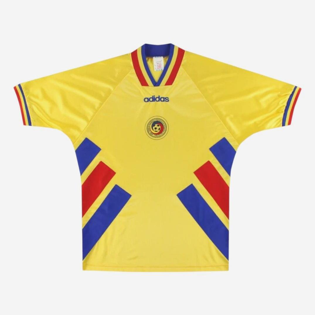 The Retro1999 Romania 1994 Home Shirt is yellow with red and blue diagonal stripes, a central national football crest, blue logo below the collar, and short sleeves featuring red, blue, and yellow retro-style trim.