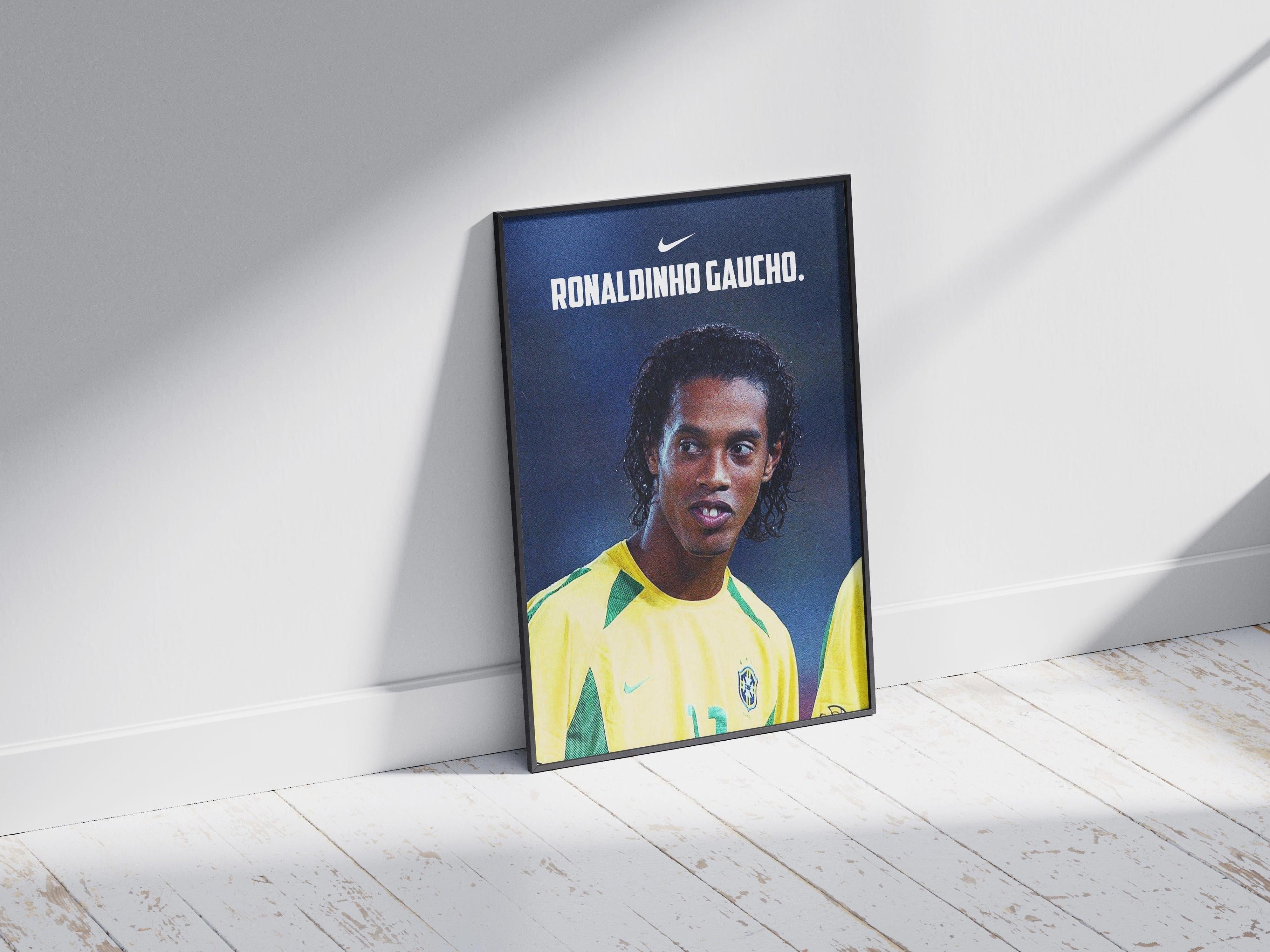The Retro1999 Ronaldinho Gaucho 2002 Poster shows the Brazilian football icon in a yellow jersey, framed and leaning against a white wall—ideal memorabilia for FIFA World Cup fans.