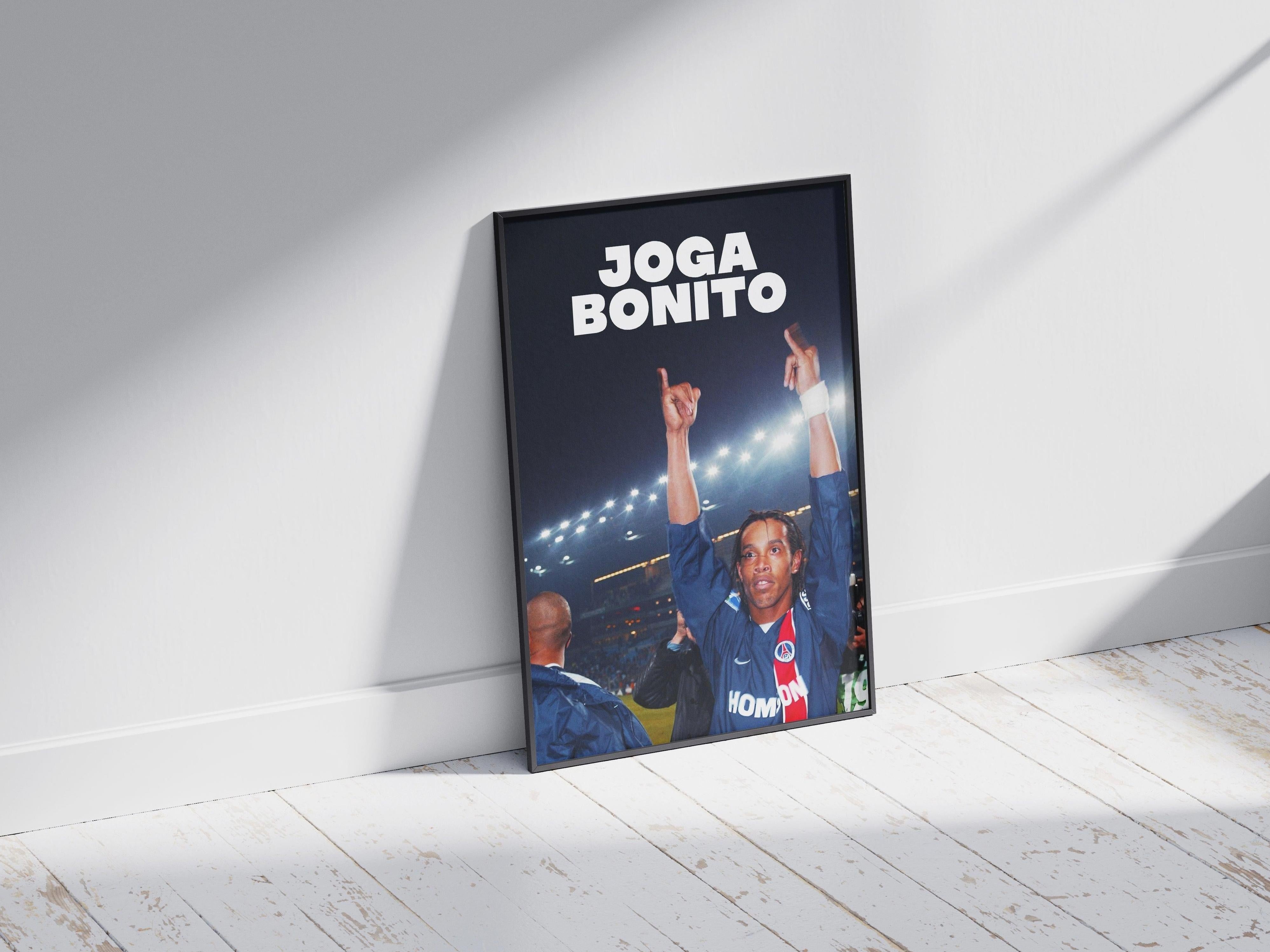 The Retro1999 Ronaldinho Joga Bonito Poster features the soccer star celebrating with both hands raised, bold JOGA BONITO text above, and glowing stadium lights and a cheering crowd in the background.