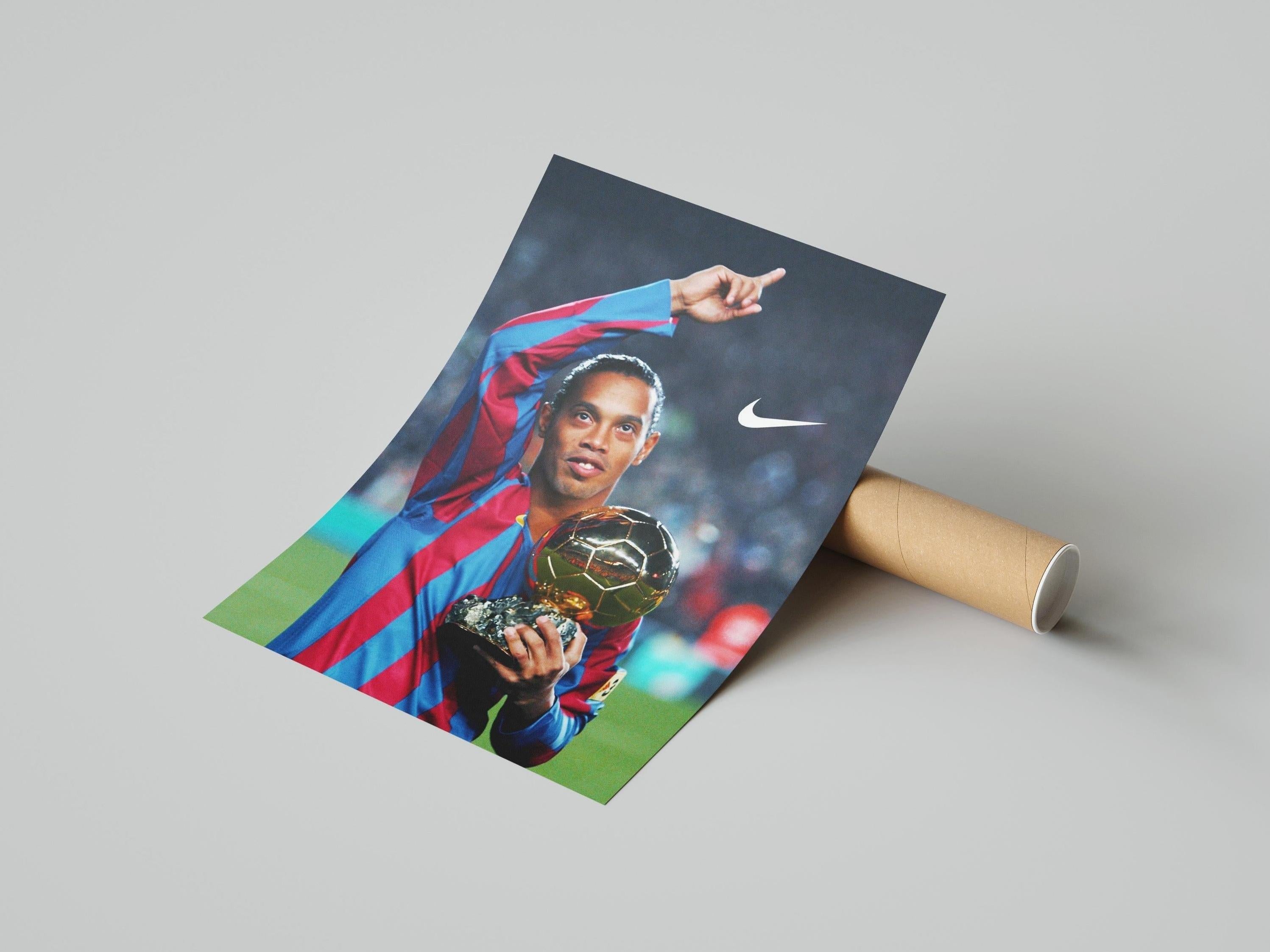 The Ronaldinho x Ballon dOr Poster by Retro1999 shows the soccer star in a red and blue striped jersey, holding the Ballon dOr trophy, pointing upward, with a visible Nike logo on the right.