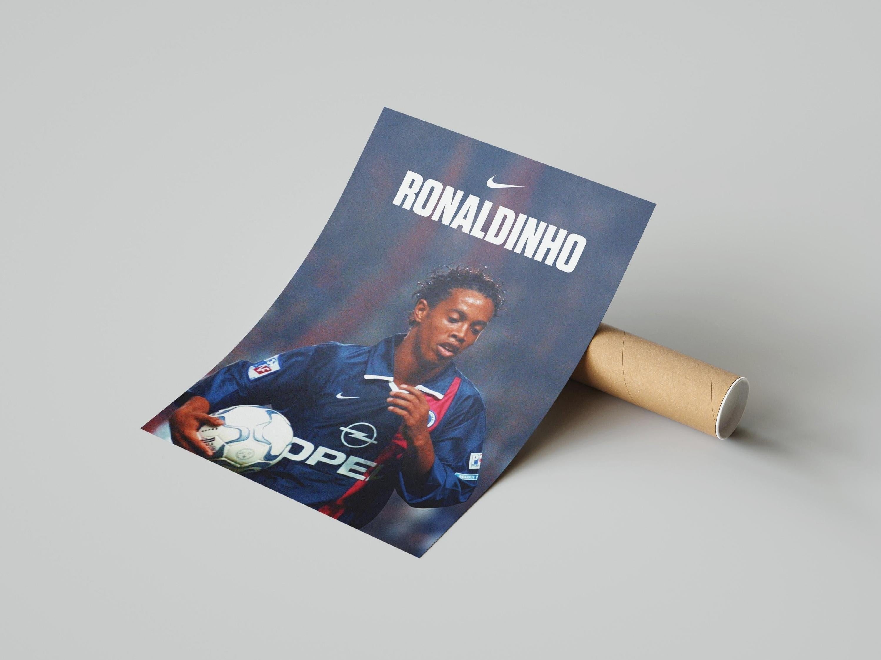 The Ronaldinho X PSG Poster by Retro1999 showcases football star Ronaldinho in a blue PSG jersey holding a ball, with RONALDINHO and the Nike logo above, presented on a light gray surface.